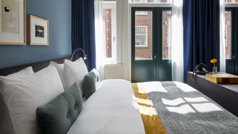 A compact guestroom features a bed with plush bedding and decorative pillows