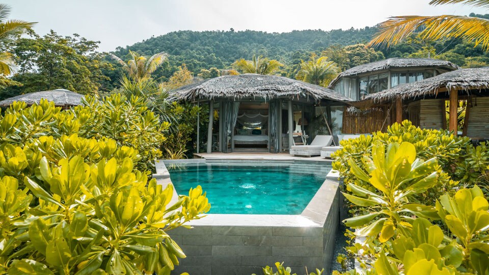 An aqua above-ground pool and thatched roof cabana are surrounded by greenery at TreeHouse Villas in Koh Yao Noi Thailand.