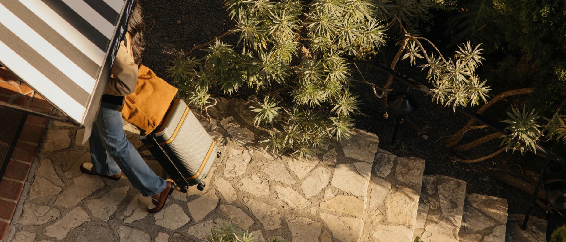 A traveller wheeling a suitcase into a hotel