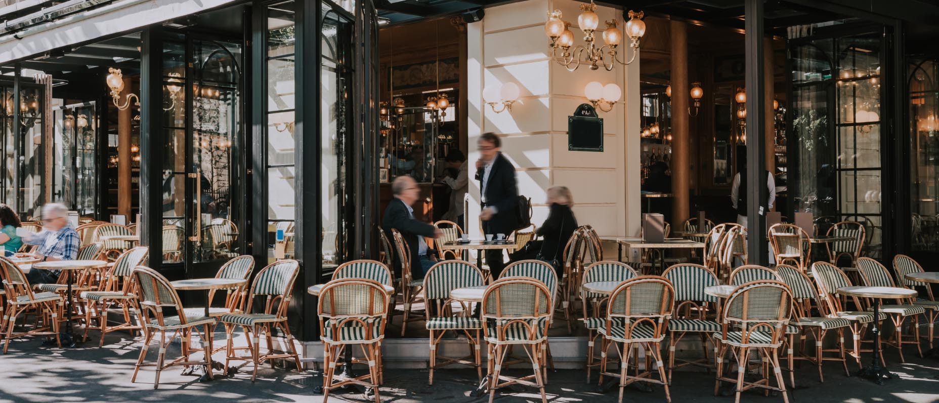 Seating outside a French-looking bisto with large doors open all around the sides and customers in motion.  