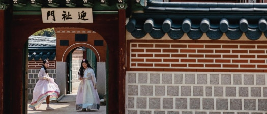 Deux personnes en costume traditionnel devant le palais de Gyeongbok à Séoul