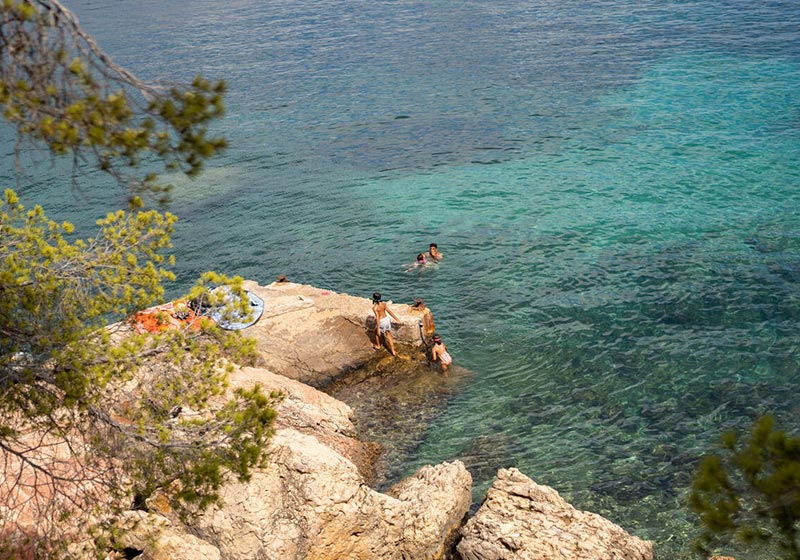 A group of people snorkelling and swimming in clear turquoise water under a bright blue sky, enjoying a summer’s day in the ocean.