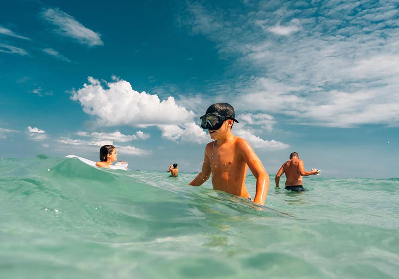 Kids playing in the ocean with sunlight and water droplets creating a summery atmosphere.