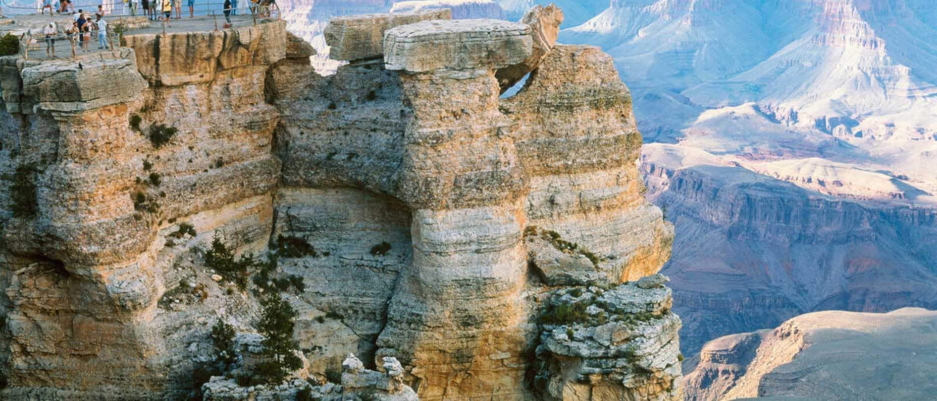 A group of travellers take in the view from the top of a rocky cliff.