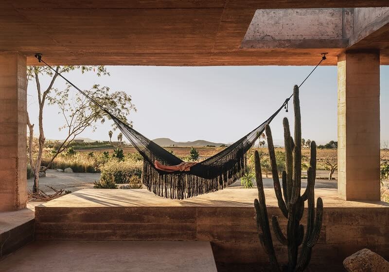 Pessoa relaxa em uma rede com vista para um deserto.