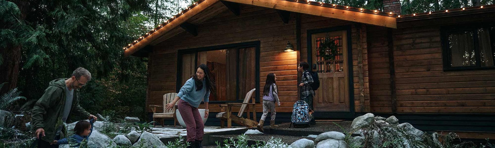 A family with three young children approaches a charming cabin in the woods.