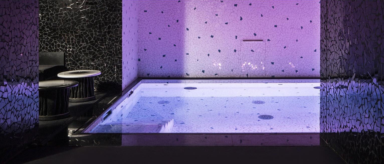 Intérieur de l’hôtel Les Bains à Paris, montrant une chambre violette dotée d’une piscine et d’un saisissant mur noir.