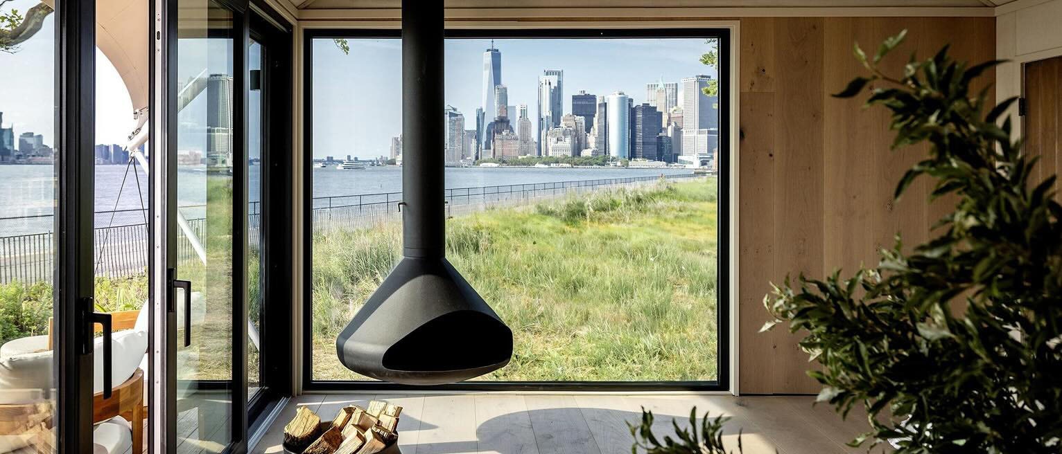 Vue intérieure d’une location de vacances au Collective Governors Island, avec vue panoramique sur la silhouette de Manhattan.