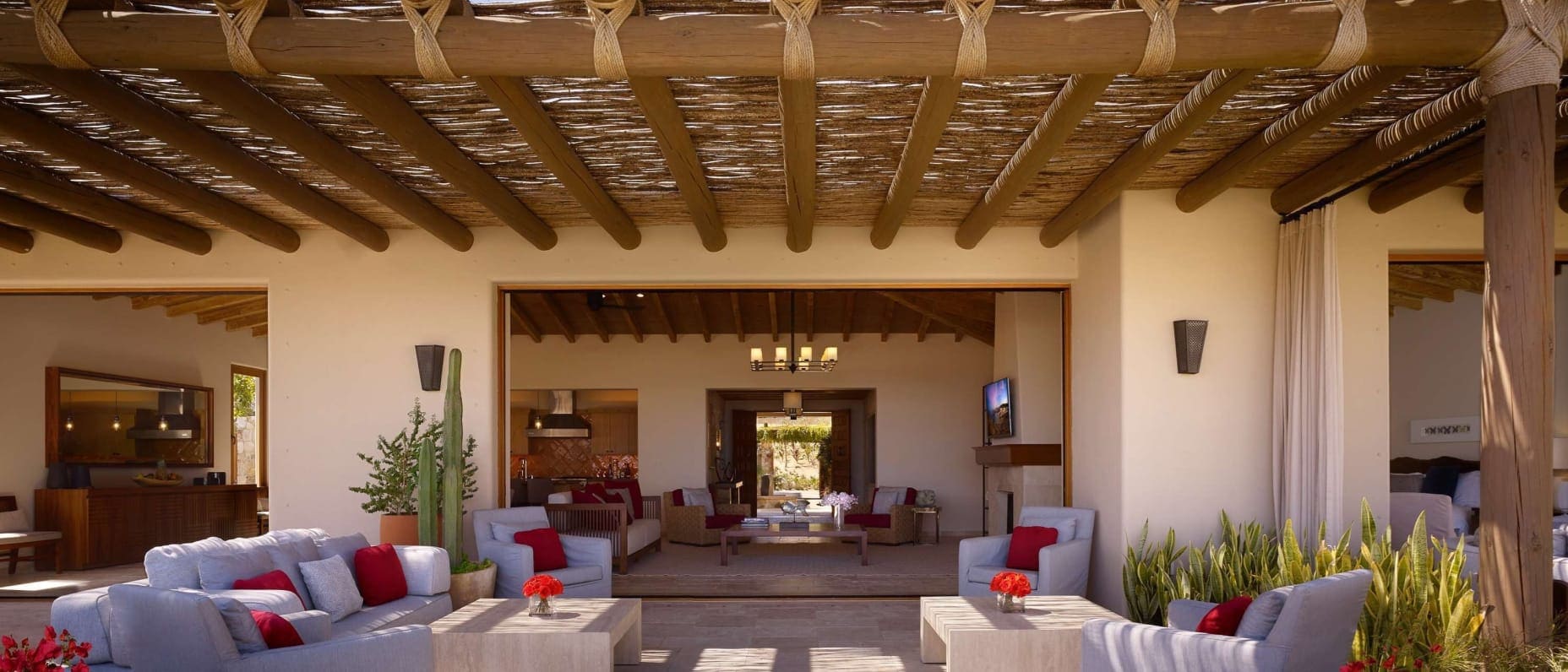 Imagem de um terraço de hotel com sofás e poltronas, telhado tramado, plantas e arquitetura elegante.