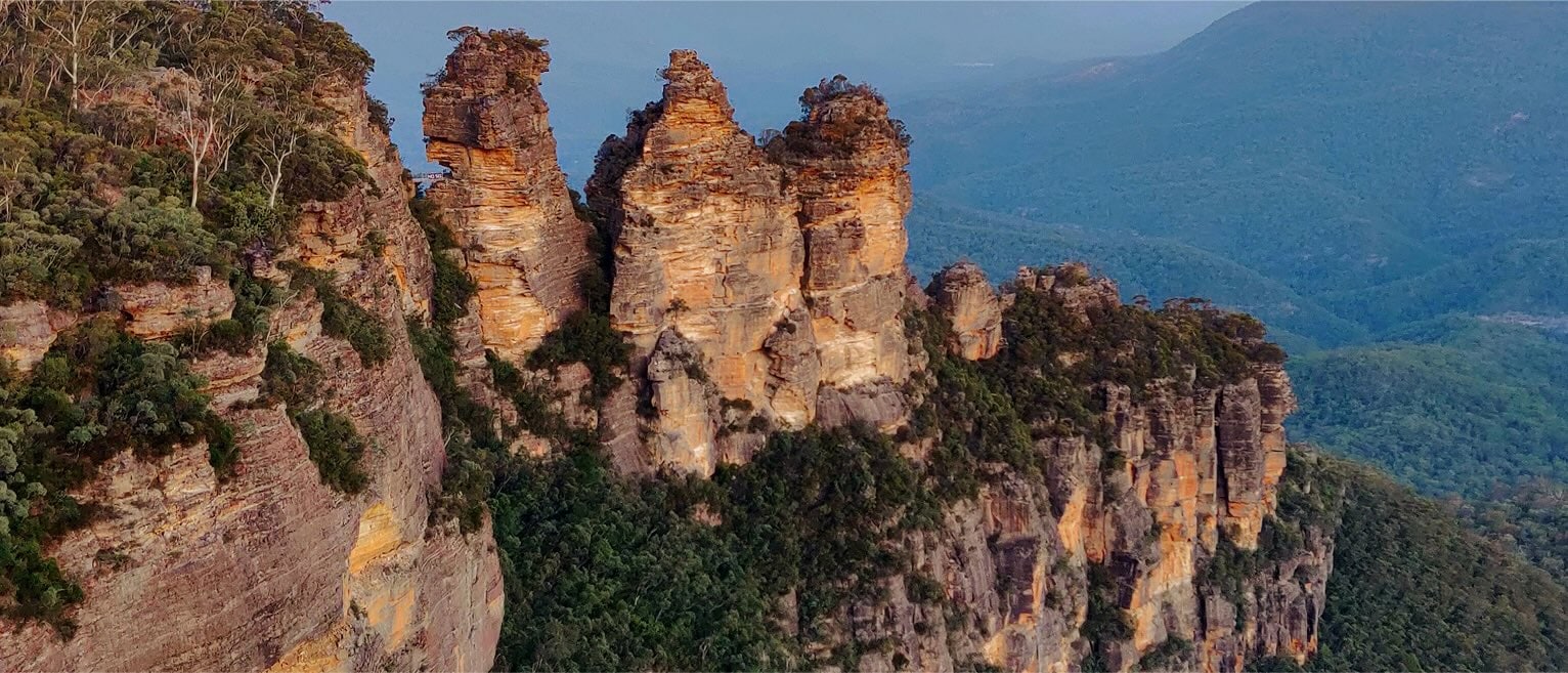 The Three Sisters rock formation rising above the forested Blue Mountains in New South Wales, Australia.
