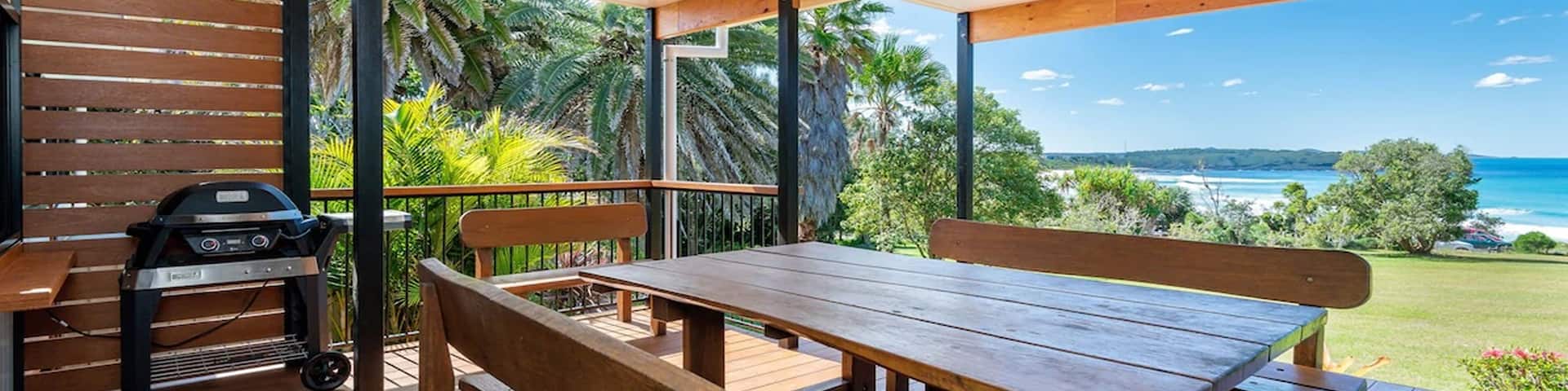 A patio with a dining table offers views of the waterfront in a tropical location.