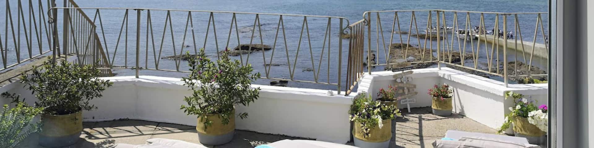 Ein Patio mit Esstisch und Blick auf das Wasser in tropischer Umgebung.