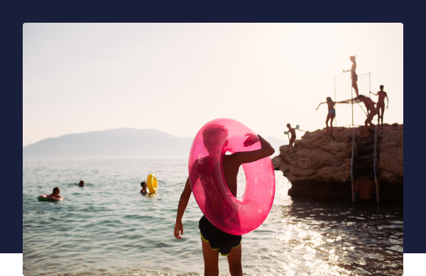 A group of children play in the sea on a sunny day with giant inflatable rings.