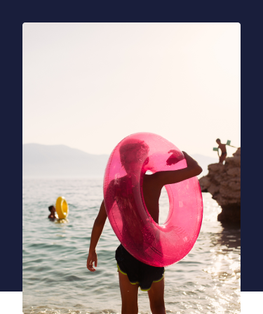A group of children play in the sea on a sunny day with giant inflatable rings.  