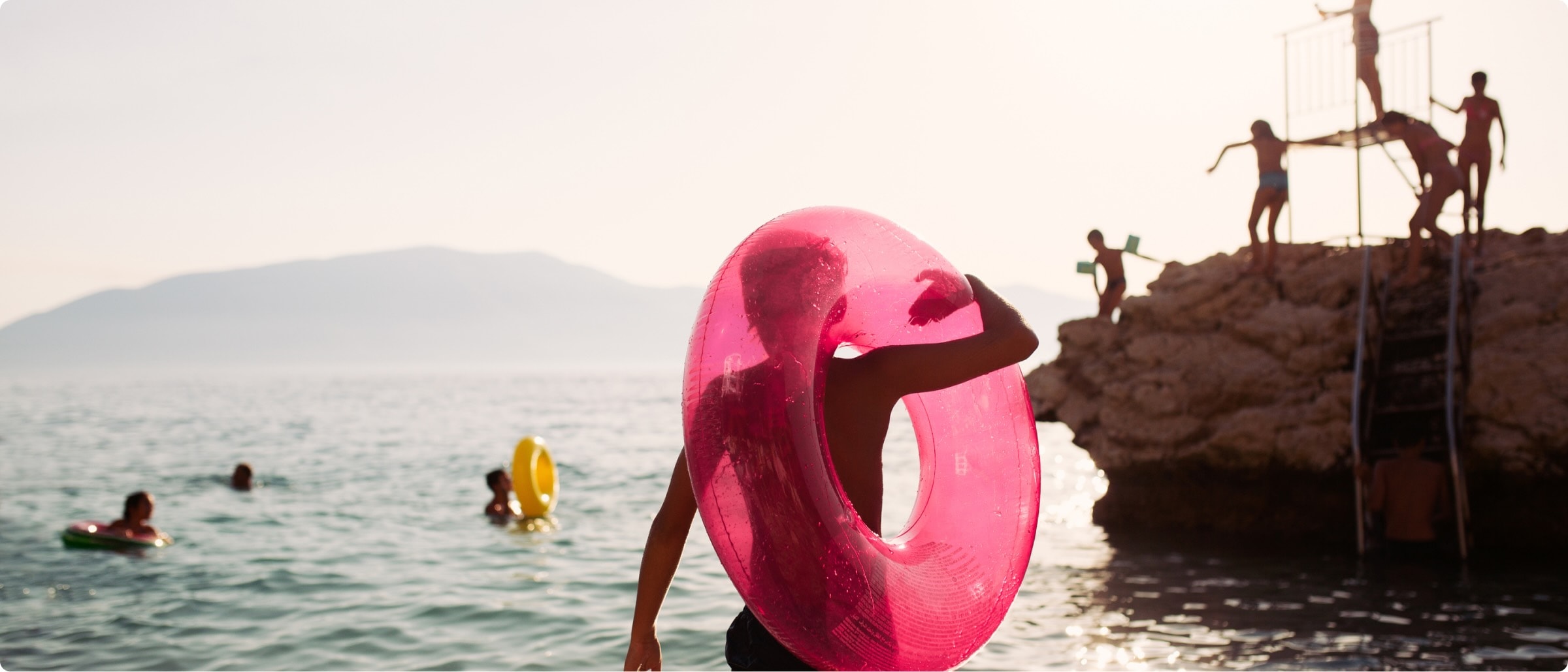 A group of children play in the sea on a sunny day with giant inflatable rings.