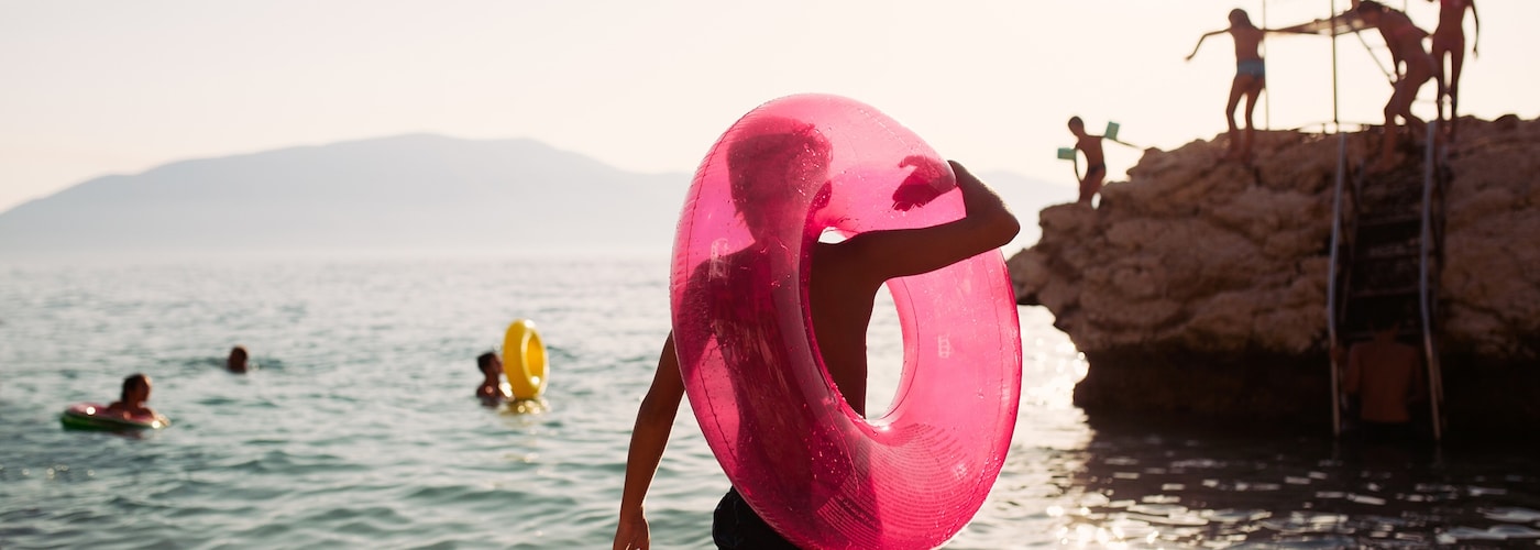 A group of children play in the sea on a sunny day with giant inflatable rings.