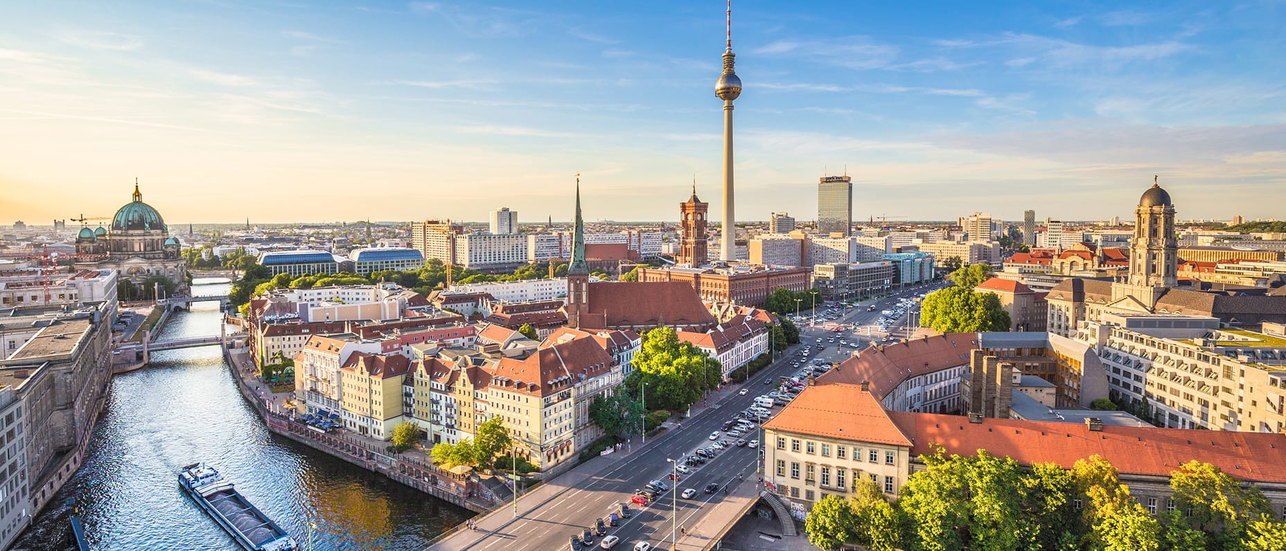 Ein Bild aus der Stadtmitte Berlins mit der Spree, dem Berliner Dom und dem Fernsehturm umgeben von historischen und modernen Gebäuden.