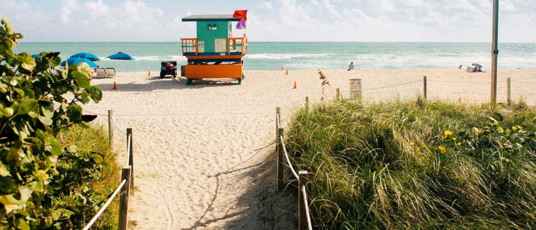 A lifeguard tower on a sandy beach with beach umbrellas