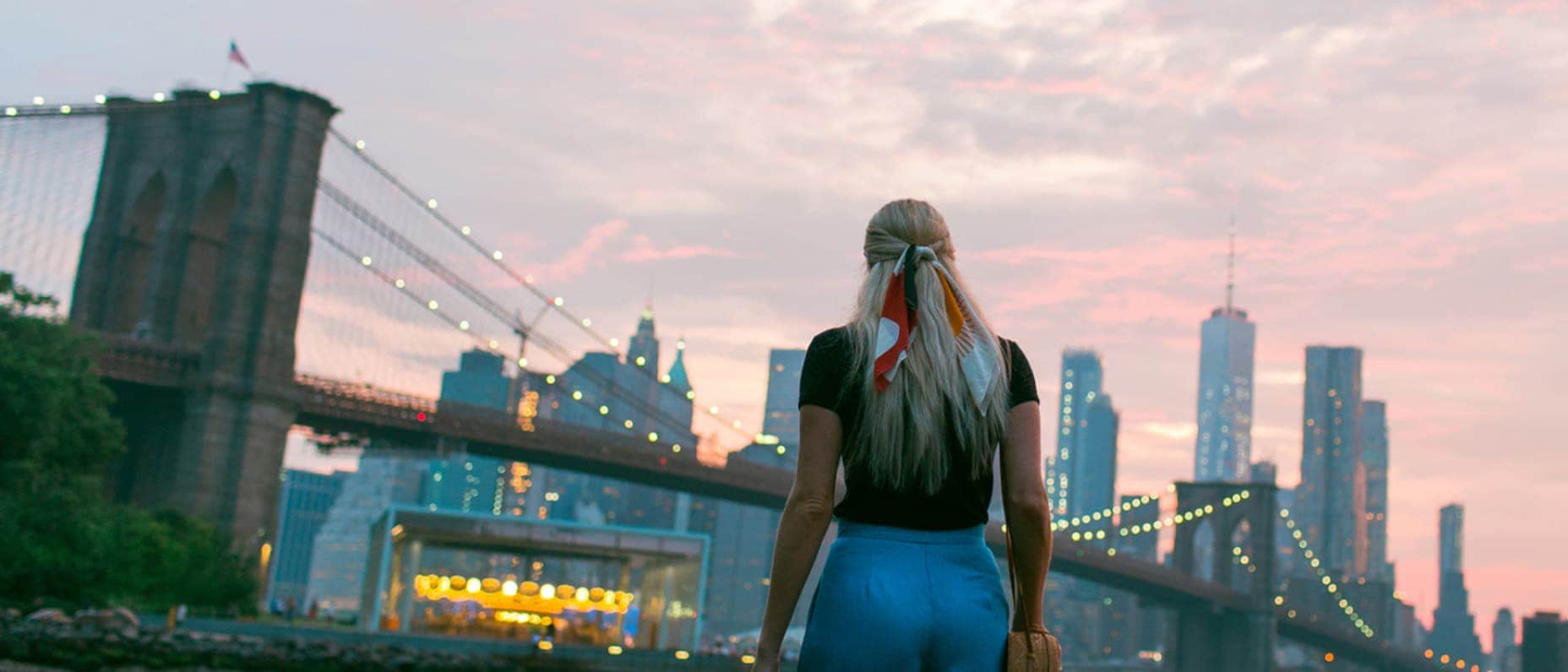A woman views the Brooklyn Bridge at dusk