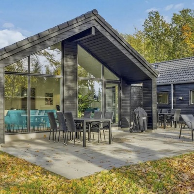 Herbstblätter umgeben eine charmante Hütte mit bodentiefen Fenstern.