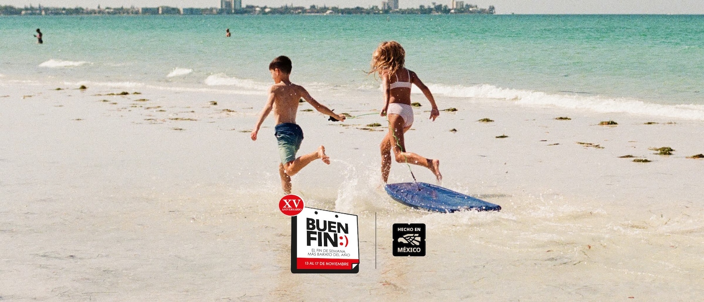 Dos niños corriendo en una playa de arena blanca y un mar azul cristalino.