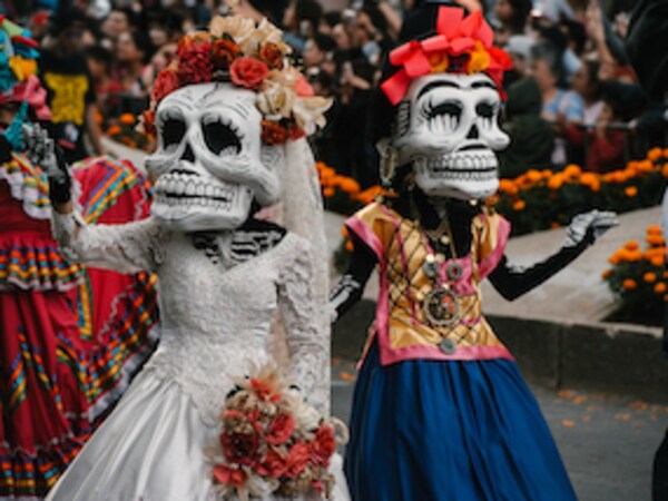 Two skeletons waving at the crowd during Día de Muertos celebrations in Mexico City