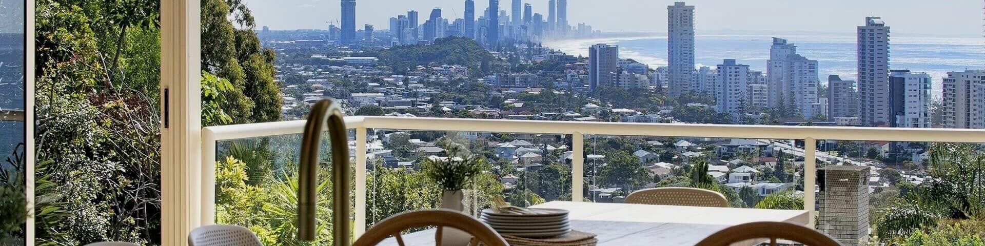 A dining table on a balcony overlooks the skyline of Gold Coast