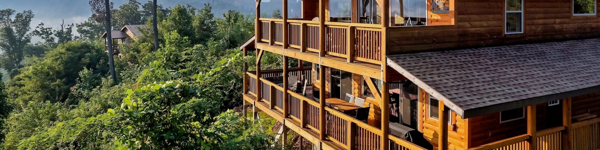 Une propriĂ©tĂ© de vacances de style chalet en bois rond dans un paysage verdoyant avec des montagnes Ă lâhorizon.