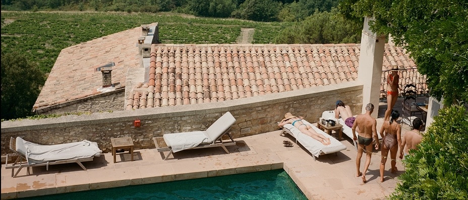 Des personnes se détendent au bord d’une piscine surplombant de vastes vignobles au cœur d’un paysage vallonné et pittoresque.