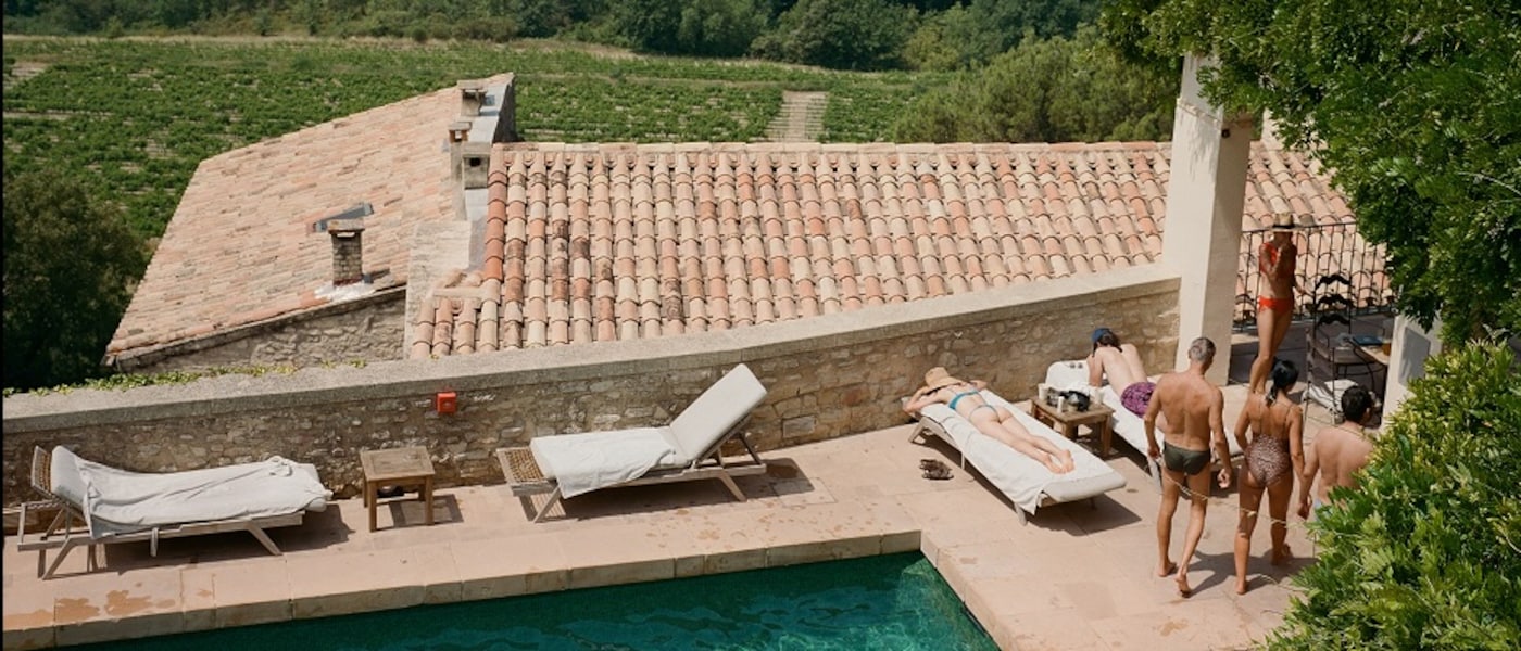 Des personnes se détendent au bord d’une piscine surplombant de vastes vignobles au cœur d’un paysage vallonné et pittoresque.