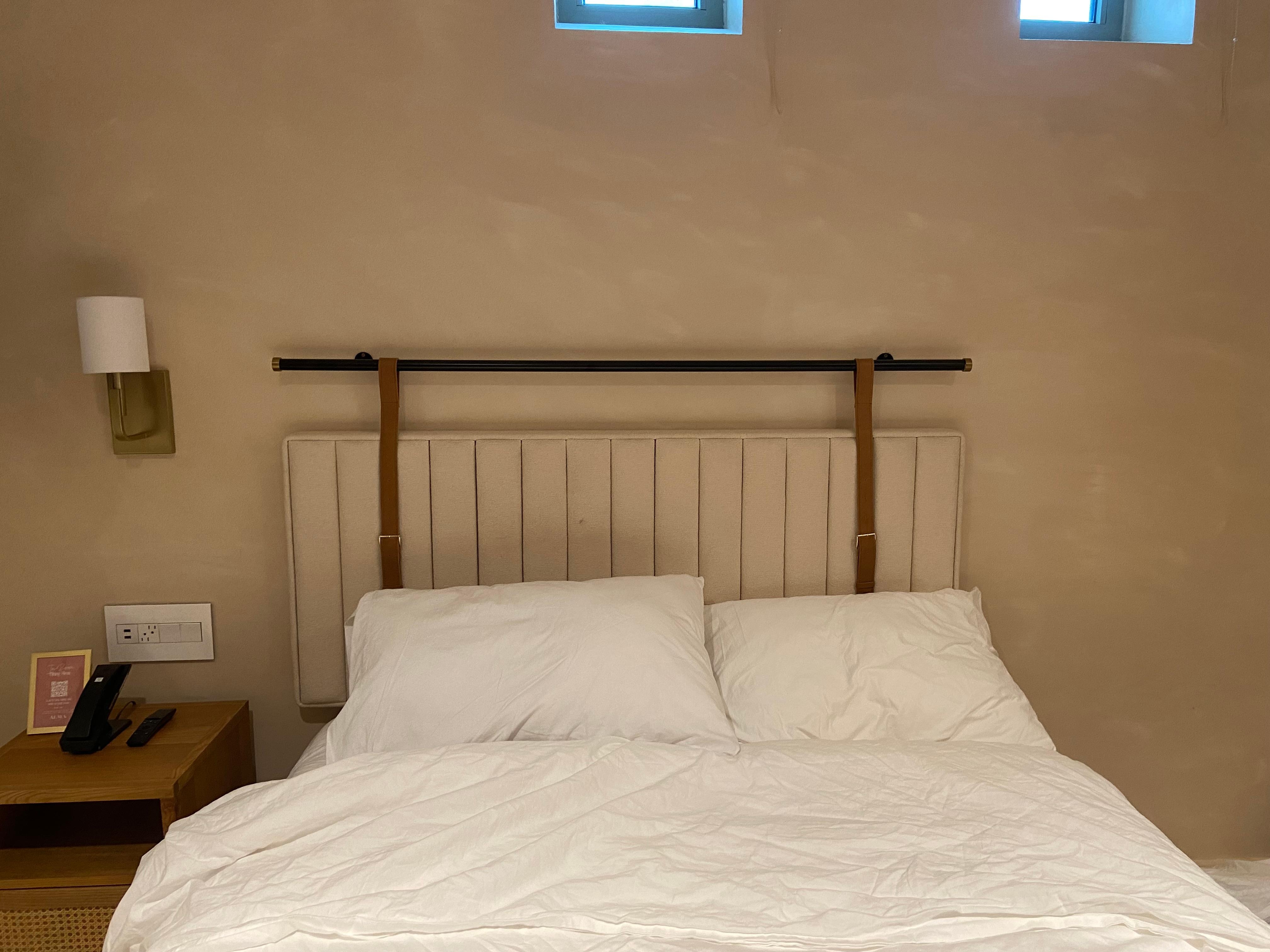 No table, no lighting fixture, no outlets on one side of the bed.