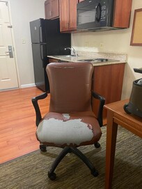 This is the chair by the table in the hotel room.