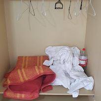LENÇOL ATIRADO NO GUARDA ROUPA JUNTO DE UMA GARRAFA DE REFRIGERANTE.