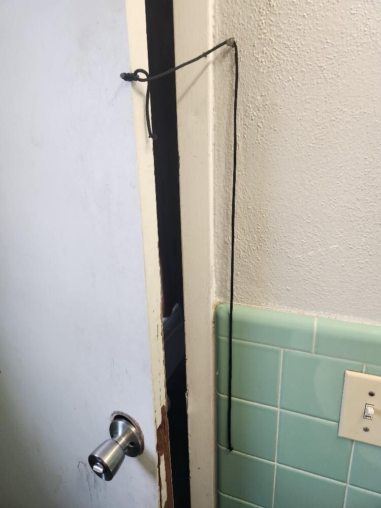 Bathroom door #3 - string used to close the door and as you can see the door does not fully close because the door is falling apart