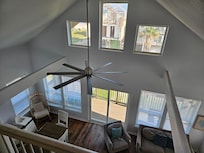 View from top floor looking over living room and windows out towards front of home and beach area