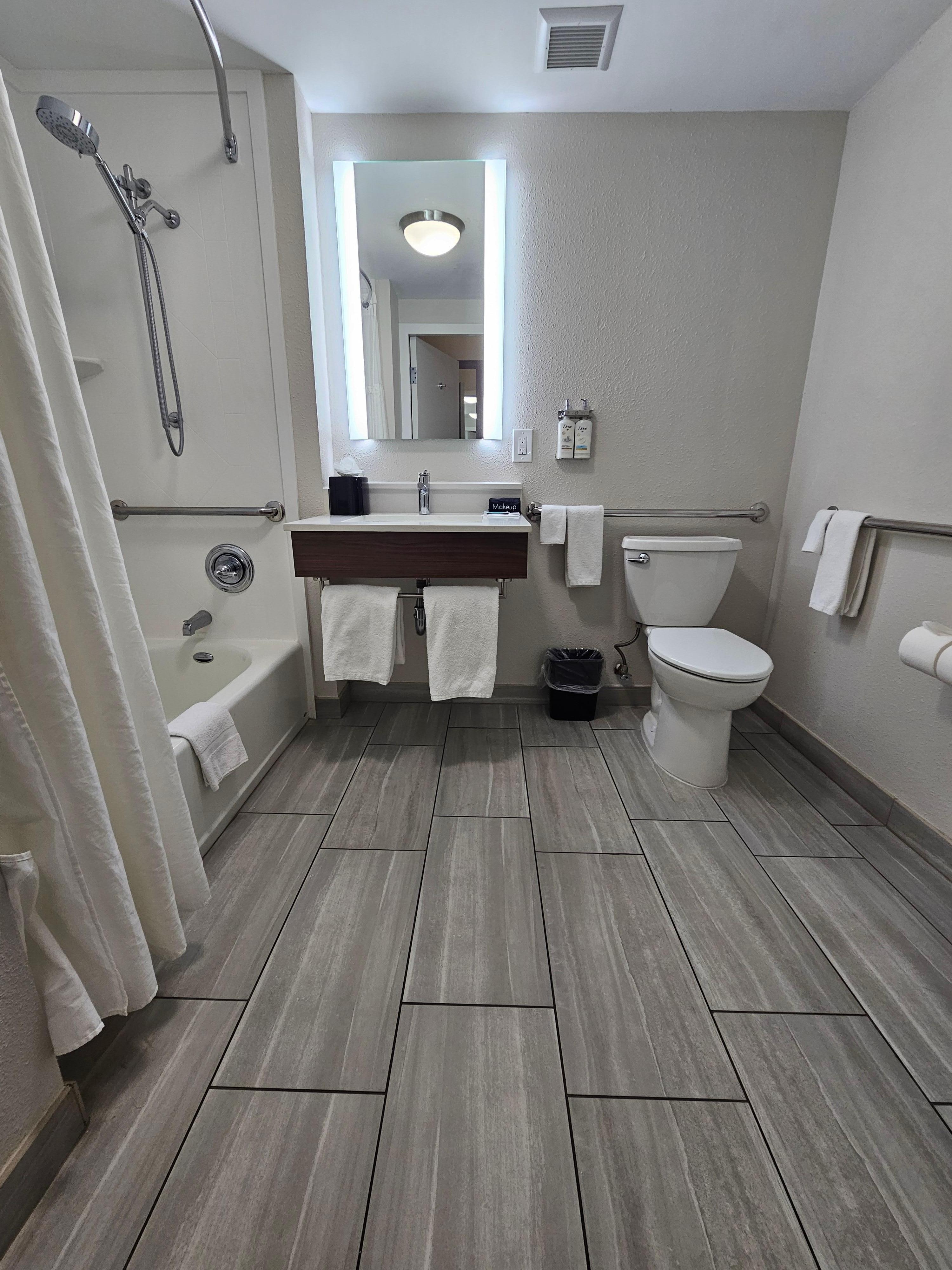 Really nice bathroom with accessible handles and shower bench. 