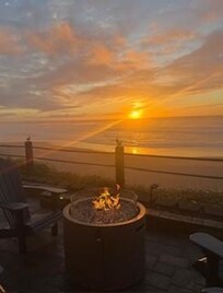 Back patio with 3 propane fire pits right next to the ocean and the sunset. No filter.
