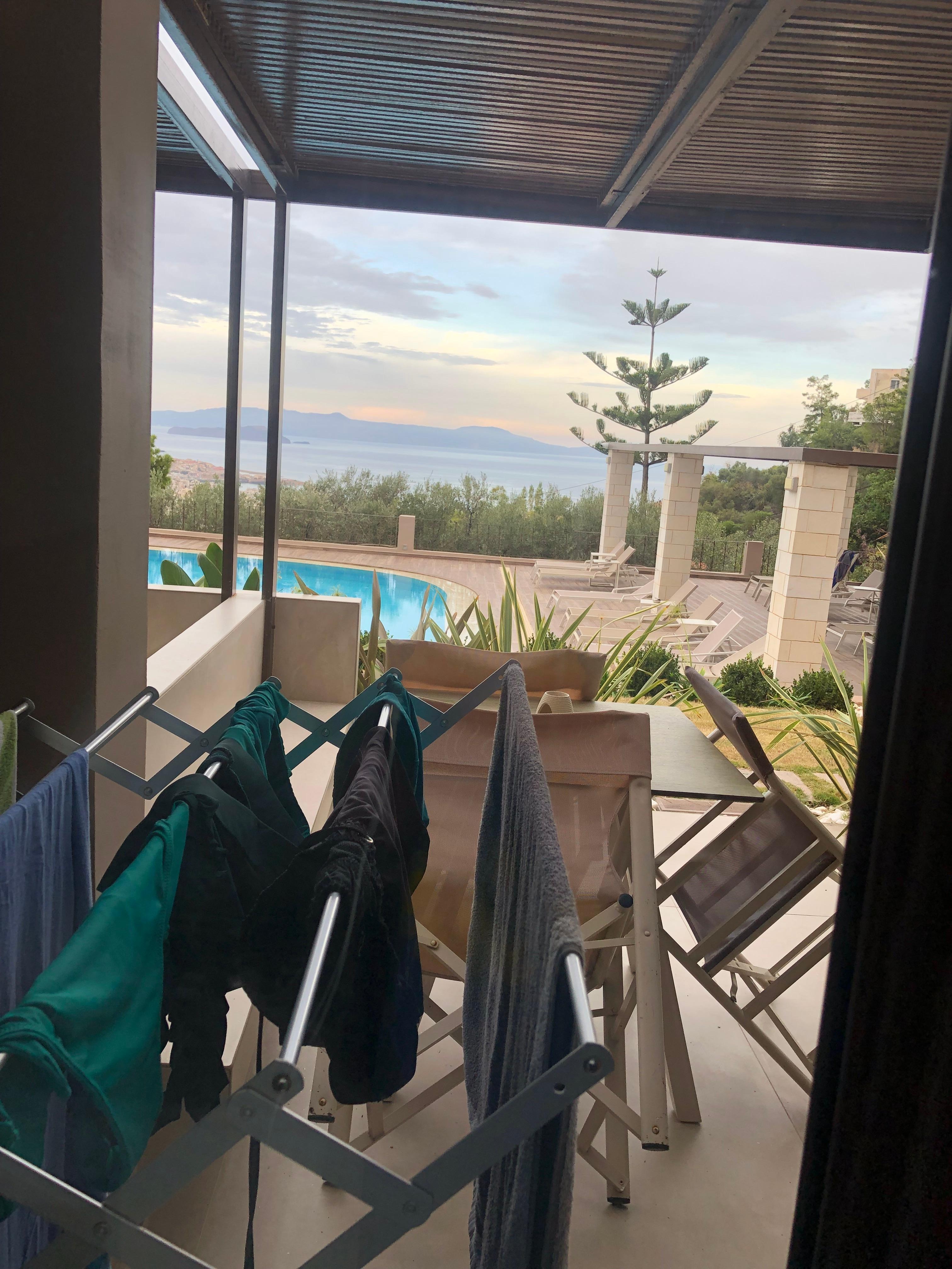 Utsikt från sängen över patio mot poolområde. 