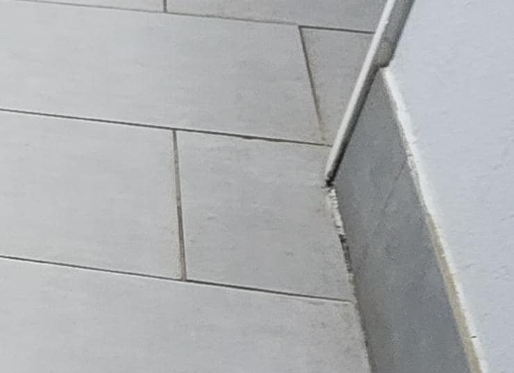 Dirty area of floor and smears on baseboard around bathroom entry