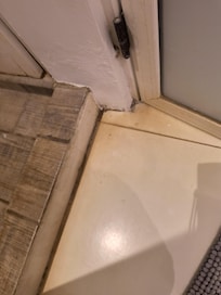 Dirt/ stained flooring bathroom small hole inch off floor where ants got into room.