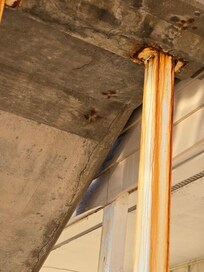 very rusty beam just outside of room supporting 2nd story at stairs..concrete looks cracked, also dangerous