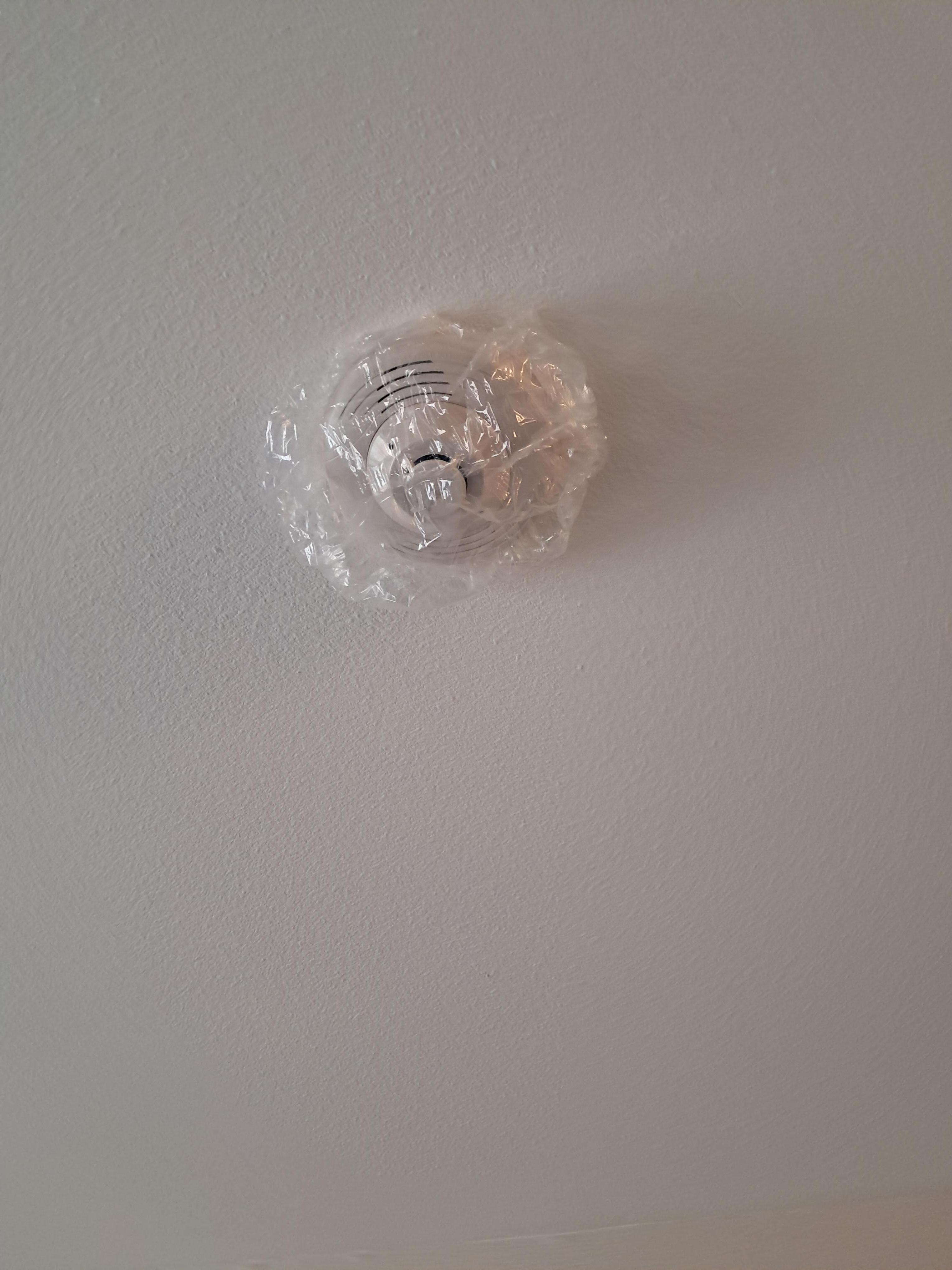 Smoke detector covered with plastic in room. 