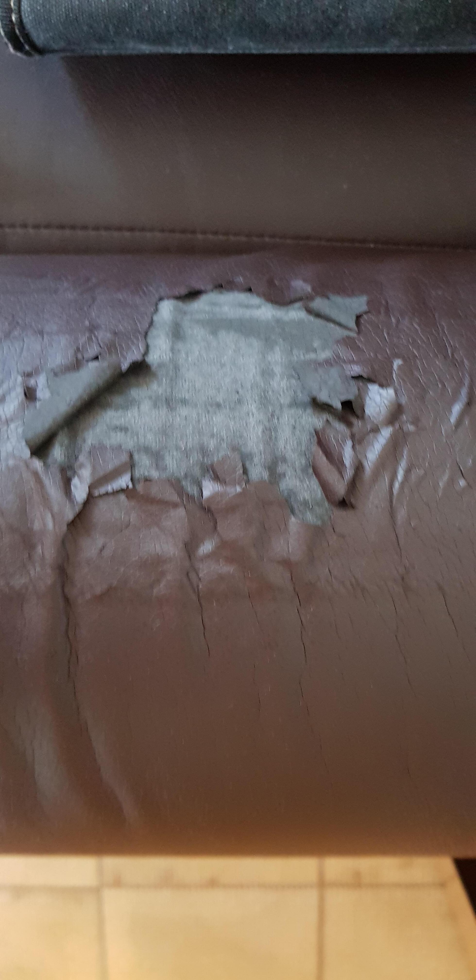 Am Sofa löst sich das Kunstleder auf, mit Decke kaschiert. 