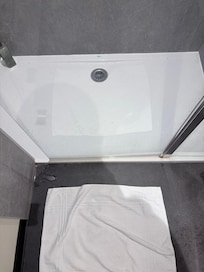 Porte de douche trop courte. L’eau passe entre le mur et la porte. Cela inonde le sol de la salle de bain