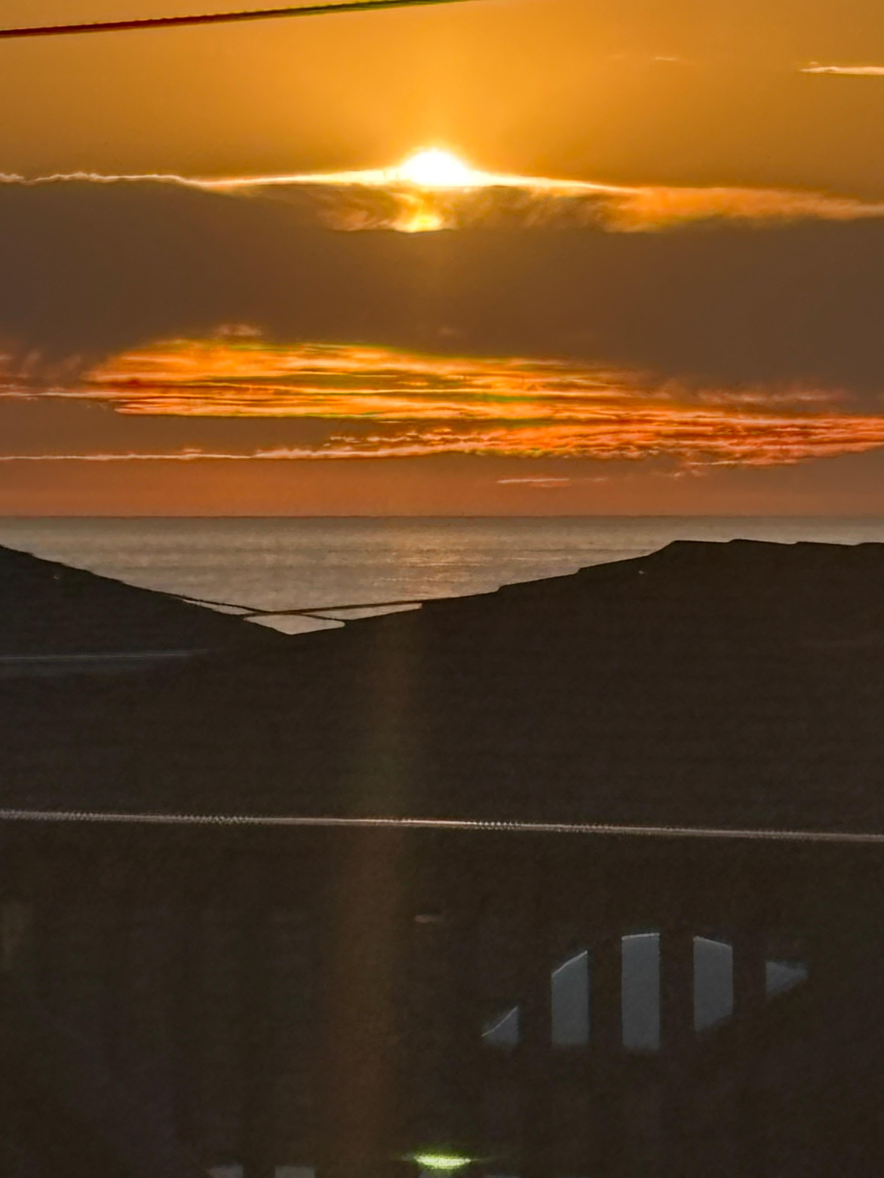 Sunset view of ocean from rooftop deck.