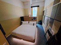 Room 274 main area with storage, fridge and tea/coffee making facilities behind double bed.