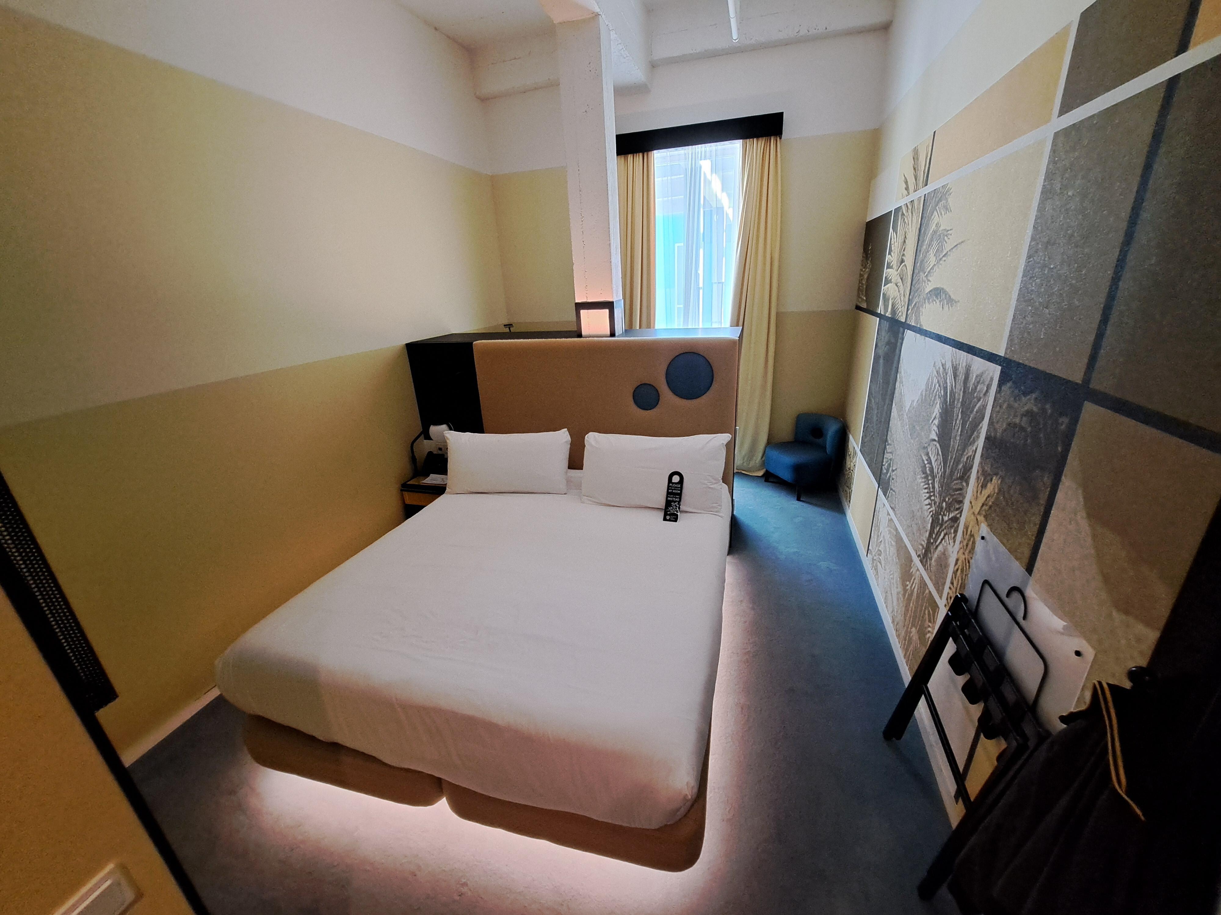 Room 274 main area with storage, fridge and tea/coffee making facilities behind double bed.