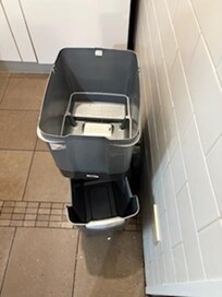 the trash can in front of the refrigerator..