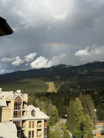 Taken from balcony. Rainbow peeking thru the clouds atop the mountains