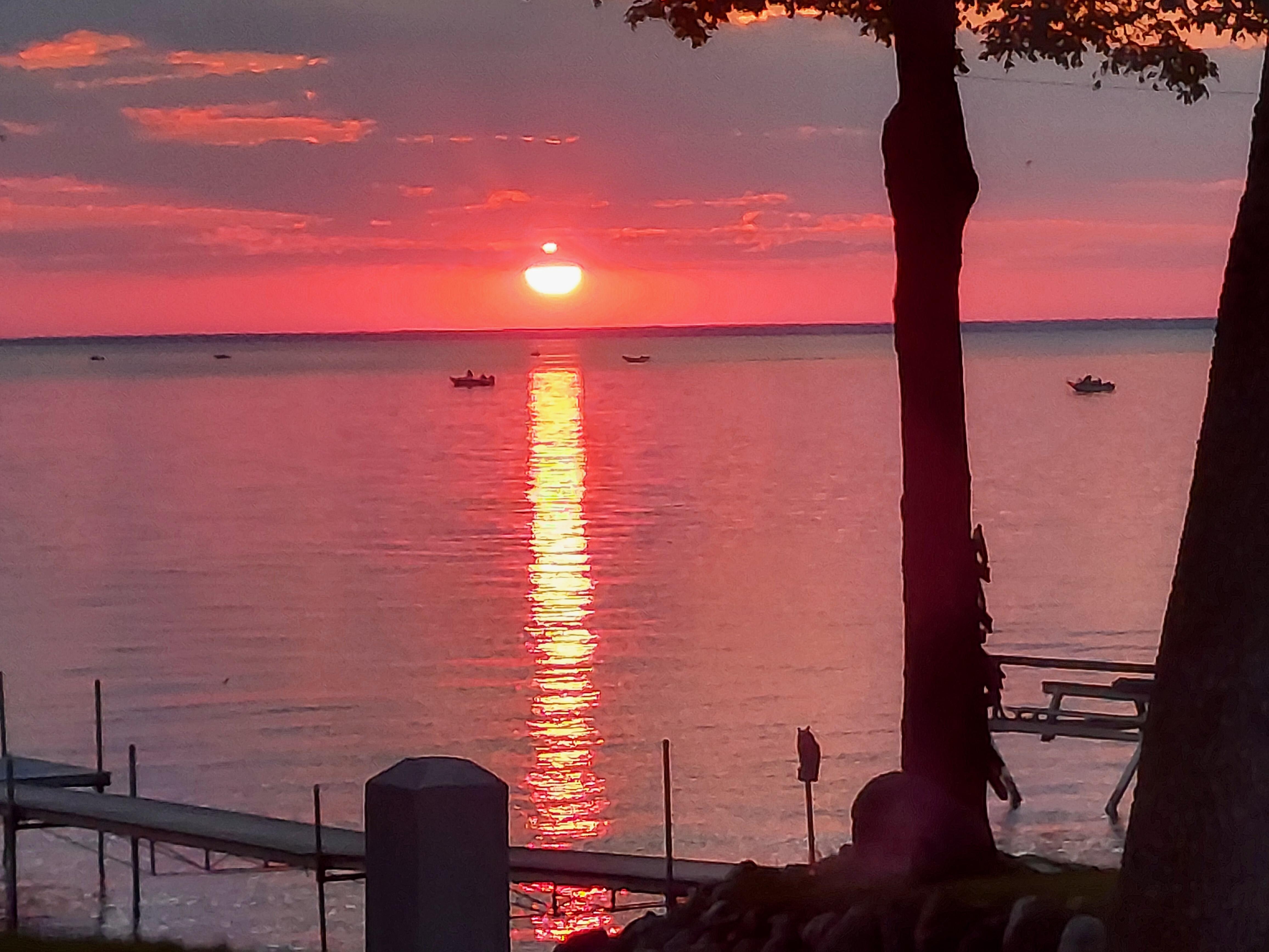 Sunset over the lake with multiple boats fishing out there.